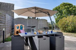 a patio table with an umbrella and a play equipment at L'Estran qu'Île - Proche plages in LʼÎle-dʼOlonne