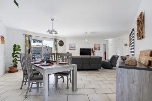 a dining room and living room with a table and chairs at L'Estran qu'Île - Proche plages in LʼÎle-dʼOlonne