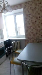 a kitchen with a table and chairs and two windows at Apartment on Chapaeva in Borisov