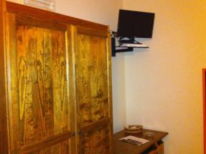 um quarto com uma porta de madeira e uma televisão na parede em Hotel Giulia em Ustica