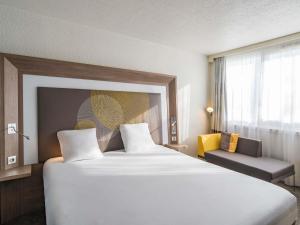 ein Hotelzimmer mit einem großen Bett und einem Fenster in der Unterkunft Novotel Le Mans in Le Mans