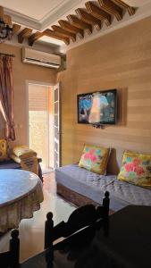 a living room with a couch and a tv on the wall at Appement in Agadir nʼ Aït Sa
