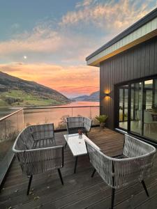 three chairs and a table on a deck with a view at Olden house fjord and sunset in Stryn