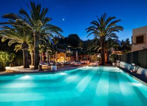 a swimming pool with palm trees at night at One Shot Buenavista in Santa Eularia des Riu