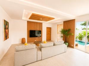 a living room with a couch and a tv at Oh’lala - 3 BR Pool Villa in Ban Tai