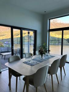 a dining room with a table and chairs and windows at Olden house fjord and sunset in Stryn