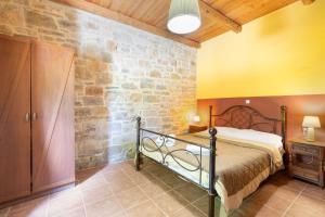 a bedroom with a bed and a stone wall at Akros Oreon, Omalos Studio in Káto Sími
