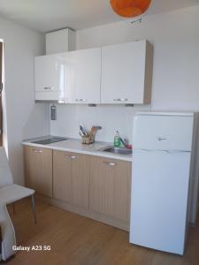 a kitchen with white cabinets and a sink and a refrigerator at Апартамент Нина in Byala
