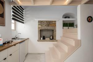 a white kitchen with stairs leading up to a fireplace at Symi Duo in Symi +19 photos