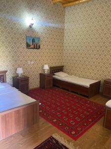 a bedroom with two beds and a red rug at TURKMAN's PALACE in Urganch