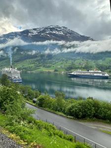 two cruise ships on the water with a mountain at Olden house fjord and sunset in Stryn +2 photos