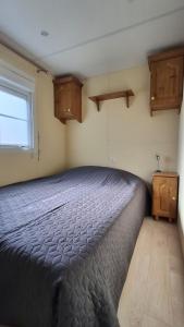 ein Schlafzimmer mit Bett, Fenster und Holzschränken in der Unterkunft Mobilehome in Weissenburg