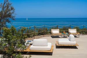 three lounge chairs and a table with the ocean in the background at Torre dei 7 Frati in Cefalù