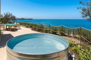 a hot tub on a patio next to the ocean at Torre dei 7 Frati in Cefalù