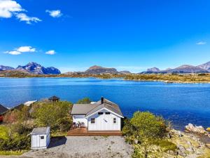 a house on the shore of a lake with mountains in the background at Lofoten Oceanfront - Privat Pier & Beach in Vestvågøya +19 photos
