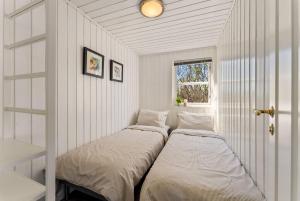 two beds in a white room with a window at Lofoten Oceanfront - Privat Pier & Beach in Vestvågøya