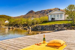 a bottle of wine sitting on a dock next to a body of water at Lofoten Oceanfront - Privat Pier & Beach in Vestvågøya
