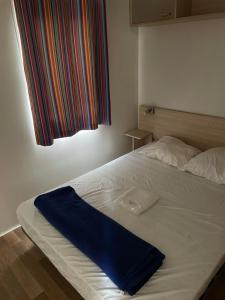 a white bed with a blue blanket on it at Camping Le Bois De Pins in Salses-le-Chateau +27 photos