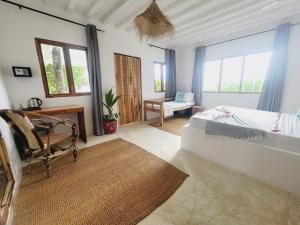 a bedroom with a bed and a chair and windows at Garden Beach Bungalows Jambiani in Jambiani