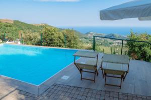 a swimming pool with two chairs and a table next to it at Agriturismo Sant'Anna in Sanremo