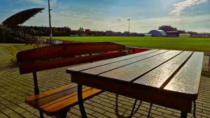 a wooden bench sitting next to a baseball field at Hotelik MOSiR Reda in Reda