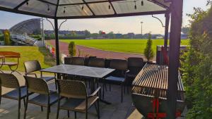 an outdoor patio with tables and chairs and a field at Hotelik MOSiR Reda in Reda