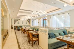 a restaurant with a green couch and tables and chairs at Bhagirathi By Atishay in Haridwār