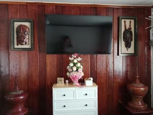 ein Zimmer mit Fernseher und einer Kommode mit Blumen in der Unterkunft BanFarang - บ้านฝรั่ง in Ban Nong Puk