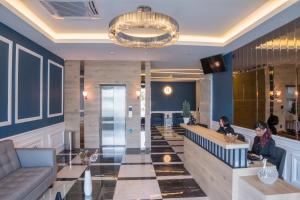 a lobby with two people sitting at a bar at Redpine Hotel in Skudai