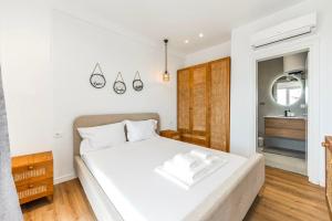 a bedroom with a white bed and a bathroom at Boho Mar Drymadhes by PS in Dhërmi
