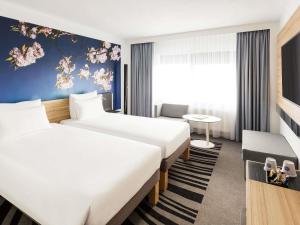 a hotel room with two beds and a table at Novotel Amsterdam City in Amsterdam +97 photos
