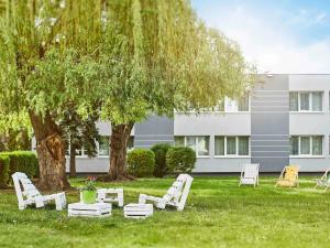 a group of chairs sitting in the grass under a tree at Novotel Wrocław City in Wrocław