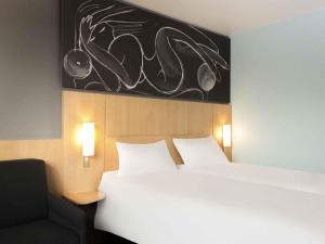 a hotel room with a bed and a chair at ibis 3 Lacs Neuchâtel in Thielle +37 photos