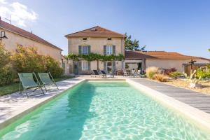 a swimming pool with chairs and a house at Au Pressoir de Boisy in Pouilly-les-Nonains