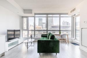 a living room with a green couch and large windows at Atlantis Suites The Entertainment District - Toronto in Toronto