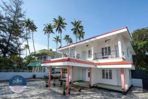a white house with palm trees in the background at Palm Beach View Resort Cherai in Cherai Beach