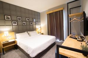 a bedroom with a bed and a desk and a television at Redpine Hotel in Skudai