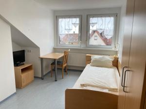 a small room with a bed and a desk and window at Gasthof Kirchberger in Fürth