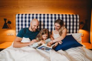 Eine Familie sitzt im Bett und liest ein Buch in der Unterkunft Hotel Bešeňová in Bešeňová