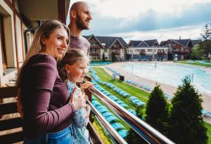 Eine Frau und ein Mann stehen auf einem Balkon und schauen auf ein Schwimmbecken. in der Unterkunft Hotel Bešeňová in Bešeňová