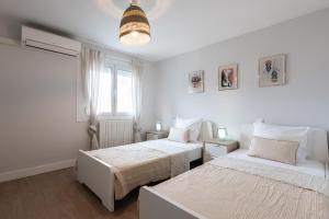 a white bedroom with two beds and a window at Villa NOVA in Capbreton