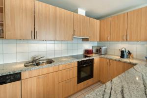 a kitchen with wooden cabinets and a sink at Haus Belvédère in Arosa