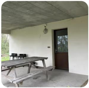 a wooden picnic table in a room with a door at Gite Rando Marquenterre in Rue