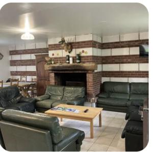 a living room with leather furniture and a fireplace at Gite Rando Marquenterre in Rue