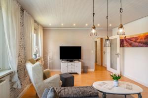 a living room with a tv and a couch and a table at Ferienwohnung am Herreder Wald in Nordhausen