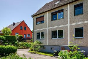 an apartment building with a red house and bushes at Ferienwohnung am Herreder Wald in Nordhausen