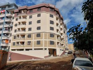 a tall white building with a car parked in front of it at Infinite Stays in Thika