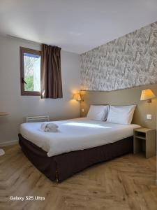 a bedroom with a large white bed with a window at Kyriad Chantilly in Chantilly