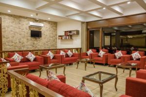 a waiting room with red couches and a tv at Summer Vines - Nashik in Pandhurli