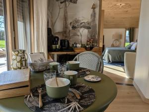 a dining room with a green table with bowls and cups at Apart'é in Saint-Brisson-sur-Loire